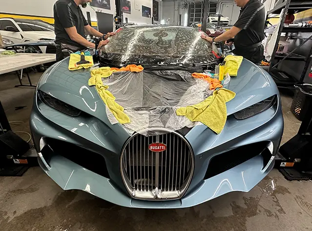 Blue Bugatti being detailed with cloths.