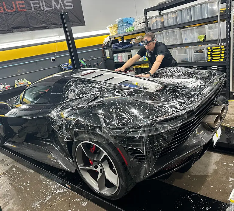 Black sports car getting a protective film.