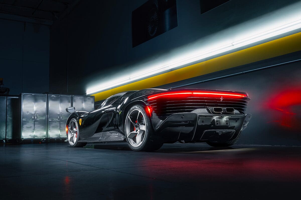 Black Ferrari in a garage with lights.