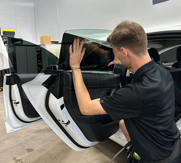 Man installing window tint on car.